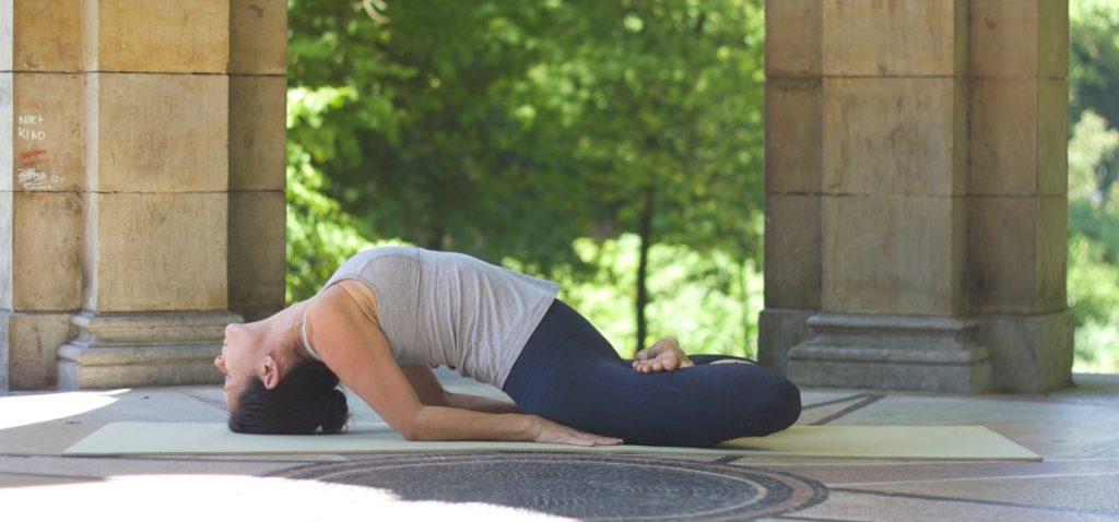 Yoga practitioner performing a gentle fish pose in a serene outdoor setting, demonstrating relaxation and flexibility in a yin yoga practice.